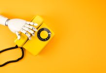 main robotique atteignant le téléphone vintage jaune